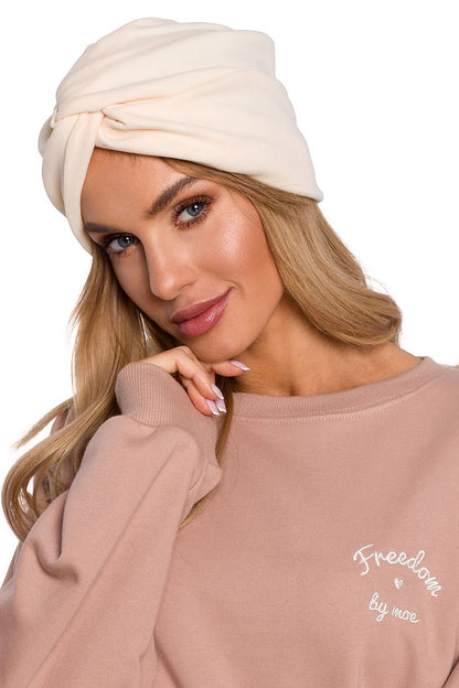 Stylish woman in a luxury lightweight knitted turban cap in soft cream, radiating sophistication and comfort from Moe.