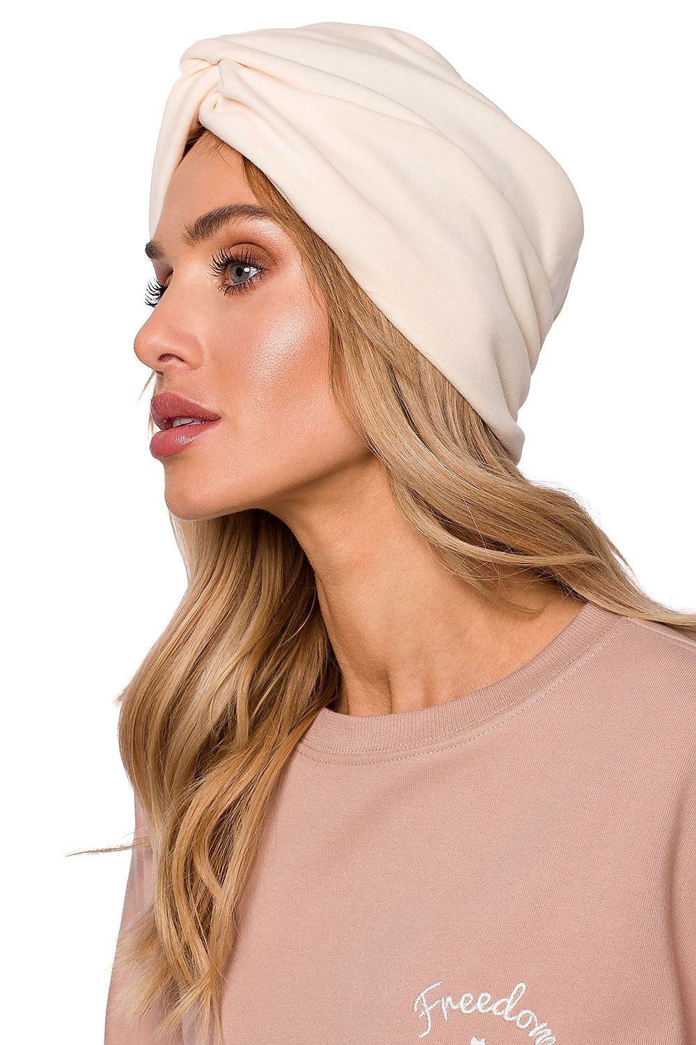 Sophisticated woman displaying a luxury lightweight knitted cap with a turban pattern in cream, ideal for cool weather by Moe.