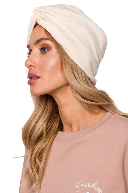 Sophisticated woman displaying a luxury lightweight knitted cap with a turban pattern in cream, ideal for cool weather by Moe.