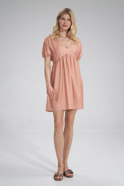 Front view of the stylish peach Daydress Figl, highlighting its relaxed fit and beautiful pleating, perfect for a refined summer ensemble.