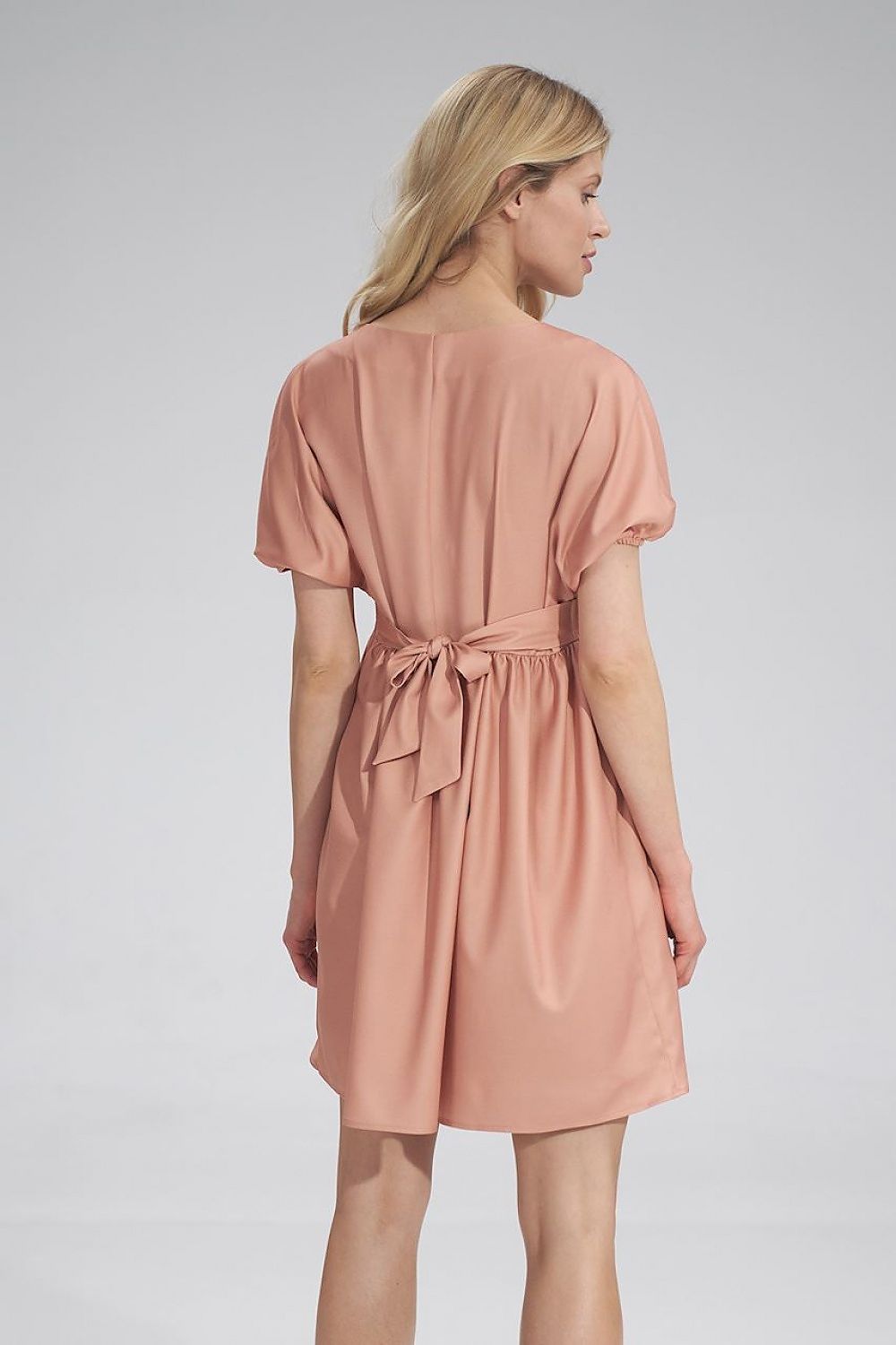 Back view of the elegant peach Daydress Figl, with a fabric belt accentuating the waist, ideal for a feminine and graceful appearance.