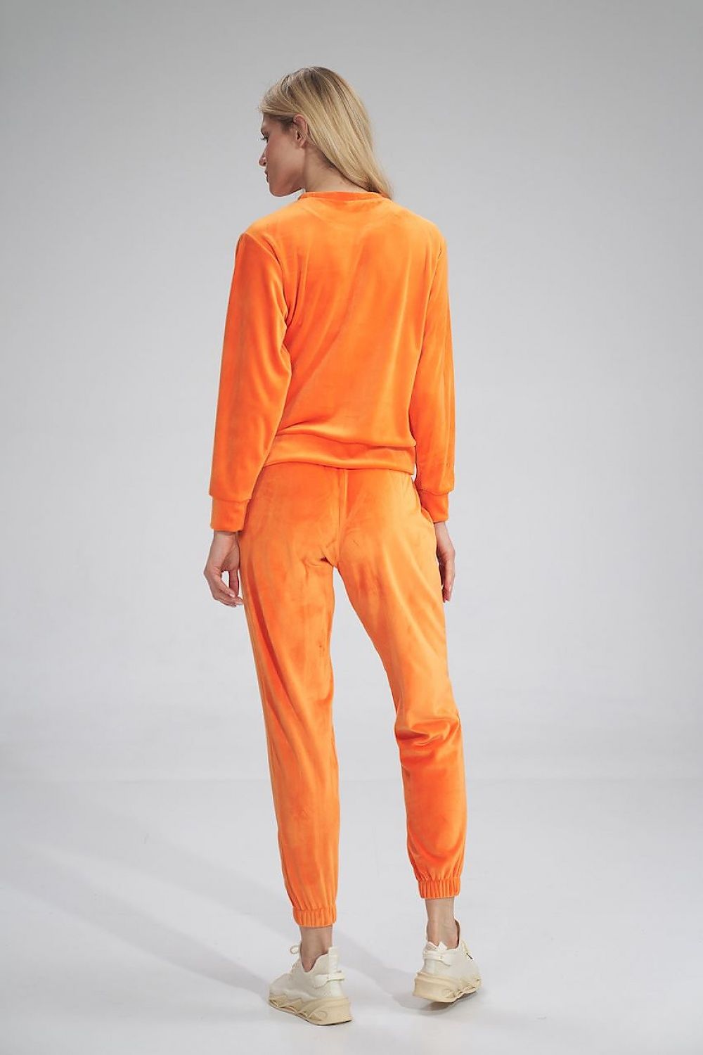 Chic model in Figl Tracksuit trousers in rich orange velour, displaying a fashionable back view, ideal for a luxurious athleisure look.