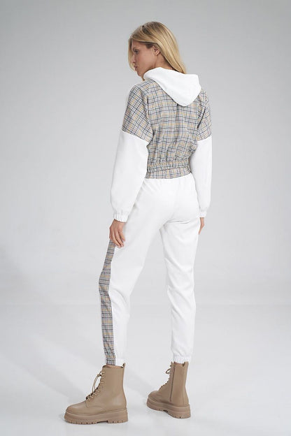 Back view of a woman in Figl tracksuit trousers with a sophisticated plaid detail, accentuating the modern athletic style while paired with chic brown boots.