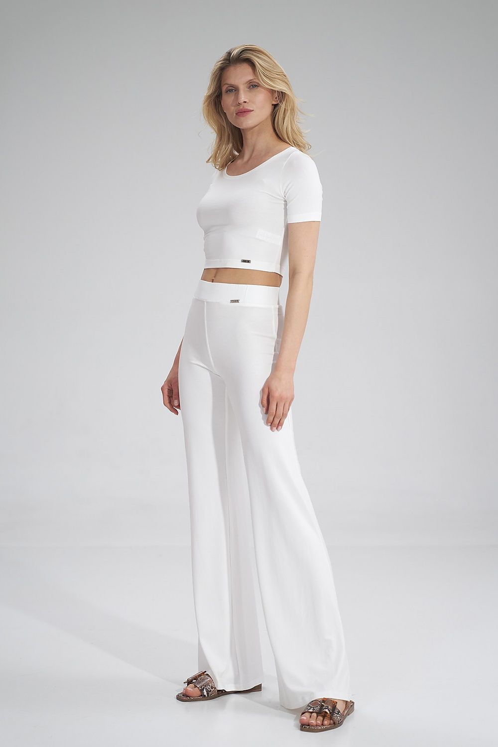 Chic white Figl blouse paired with wide-leg trousers, model presenting a sophisticated summer look.