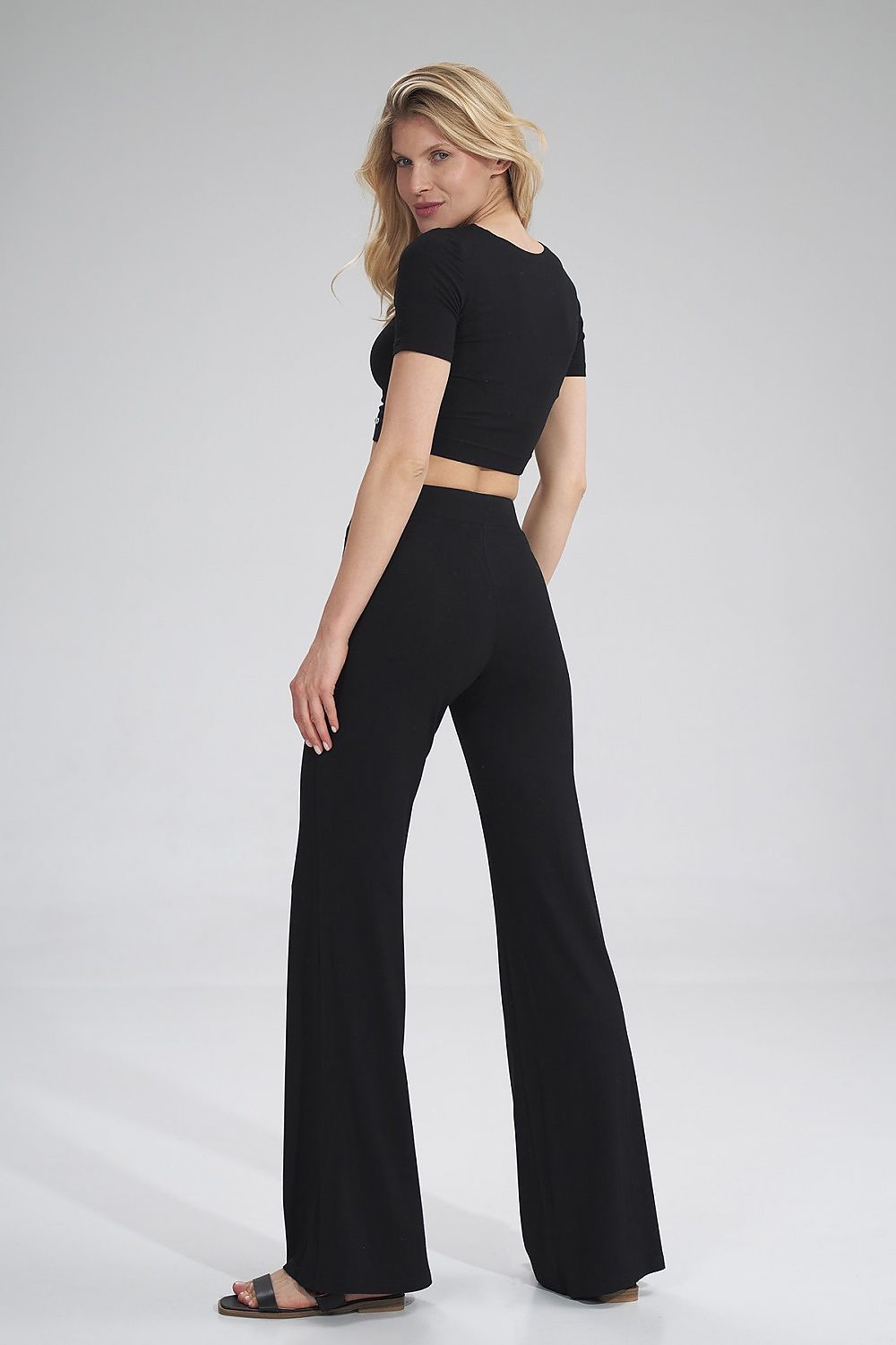 Chic rear view of a model wearing the Figl crop style blouse and flared black trousers, exuding elegance and modern sophistication.