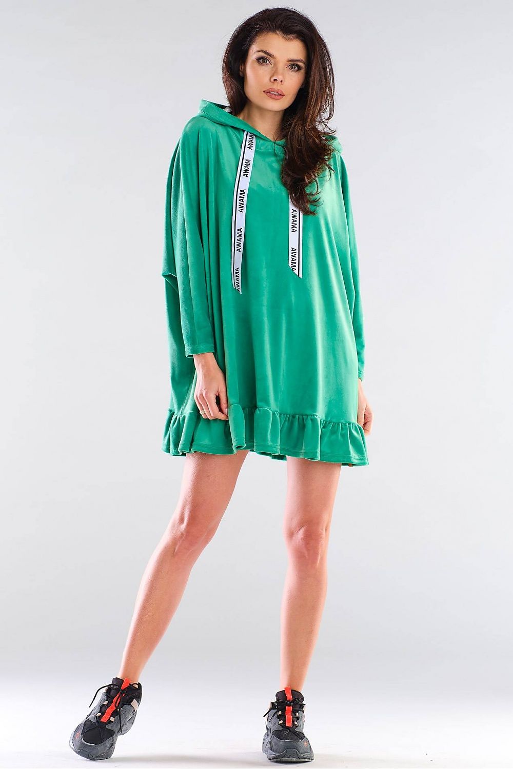 Sophisticated model showcasing the Daydress Awama in luxurious green, designed with a trendy hood and flowing silhouette, perfect for an upscale casual look.