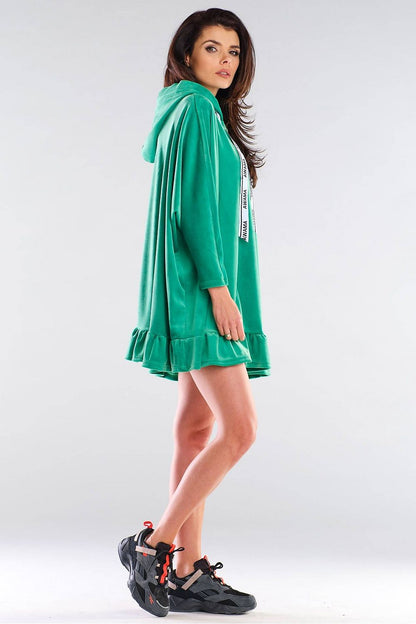 Sophisticated side view of the Awama daydress, showcasing its luxurious green fabric, oversized silhouette, and playful ruffled hem, ideal for effortless styling.