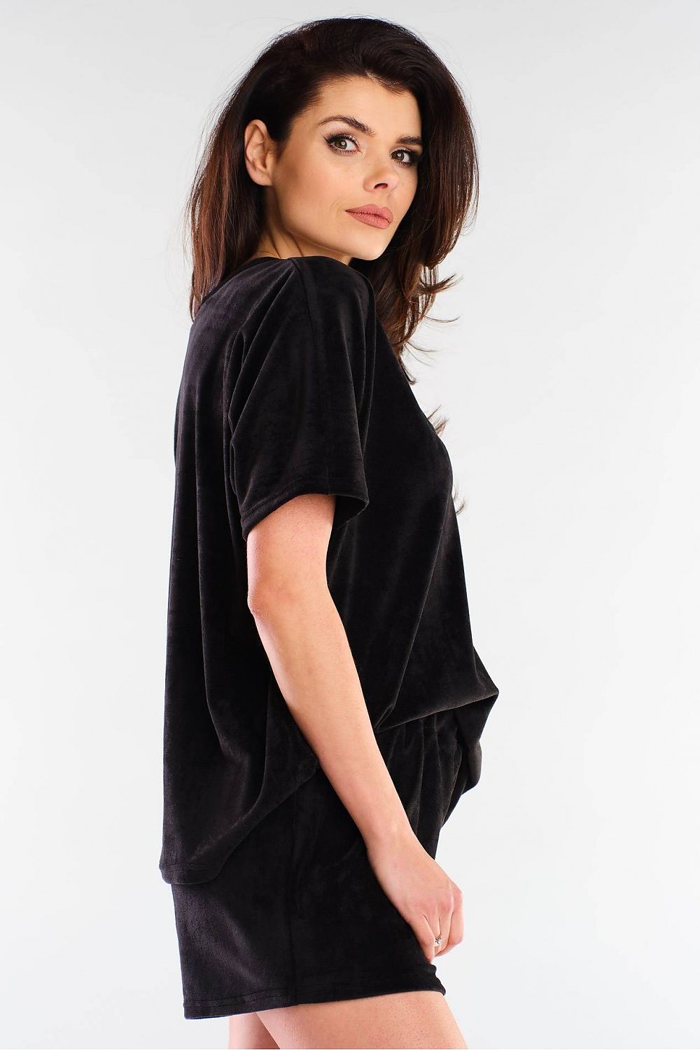 Side profile of a model wearing exquisite black velour shorts and a v-neck top by awama, reflecting a modern and stylish aesthetic.