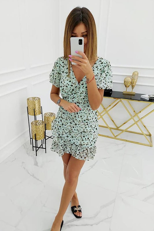 Elegant Daydress Vittoria Ventini in a floral mint design, flowing silhouette, perfect for a feminine look, showcased by a model with a smartphone in a stylish interior.