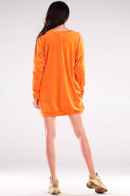 Back view of the luxurious Awama velour daydress in vibrant orange, showcasing its relaxed long sleeves and contemporary design, perfect for warm weather.