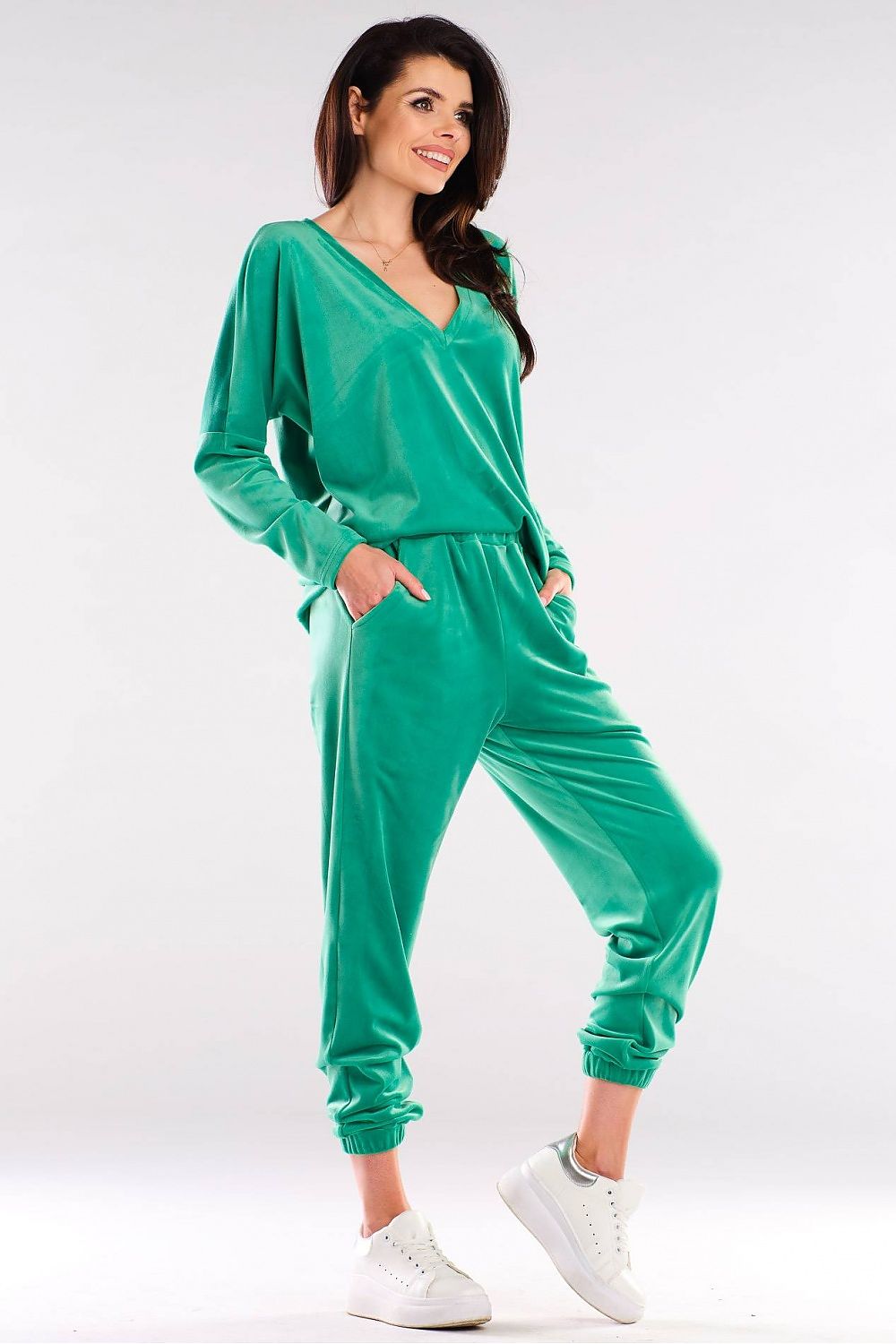 Elegant Awama women's loose-fit sweatshirt in vibrant green, featuring a heart-shaped neckline and drawstring hem, styled with casual trousers and white sneakers.