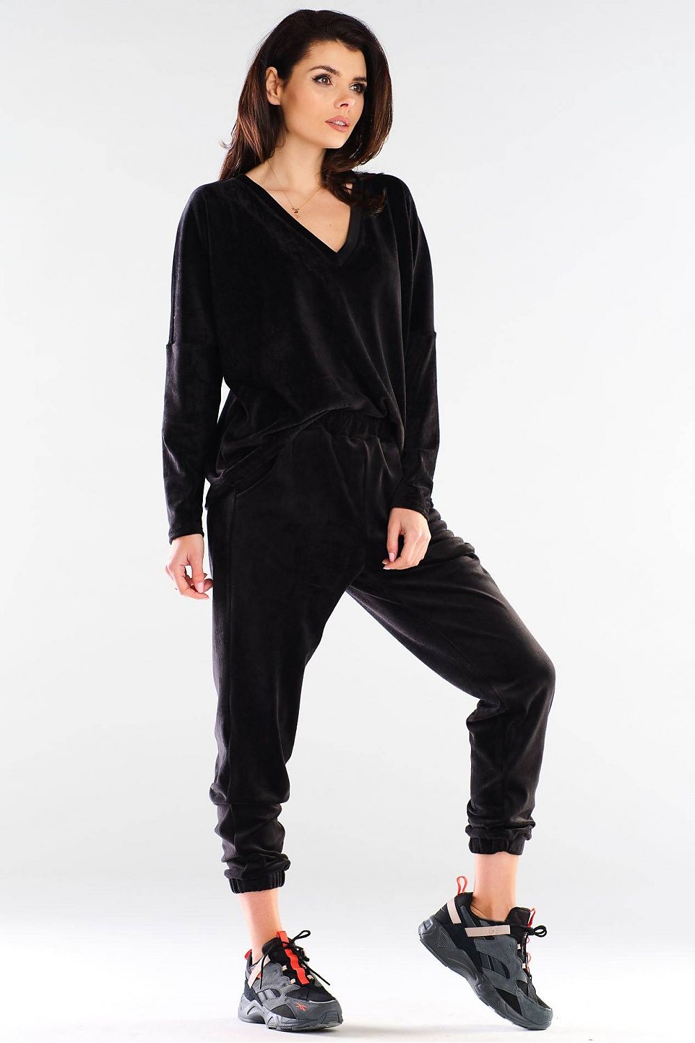 Chic Awama black loose-fit sweatshirt featuring a flattering V-neckline and stylish silhouette, accentuated by relaxed trousers and sporty footwear.