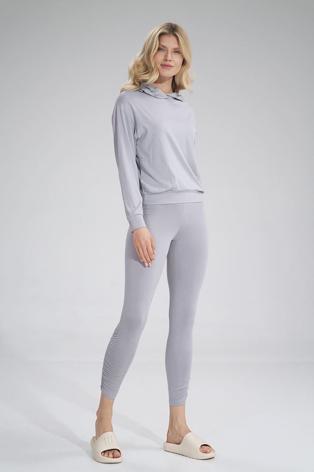 Elegant model showcasing Figl luxury long leggings with a creased design and wide waistband in soft grey fabric, exuding comfort and sophistication.