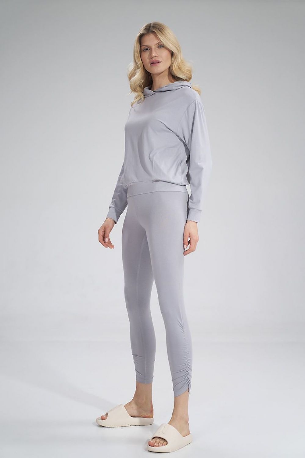 Stylish view of a woman in Figl luxury long leggings paired with a matching grey hoodie, highlighting the chic and contemporary design.