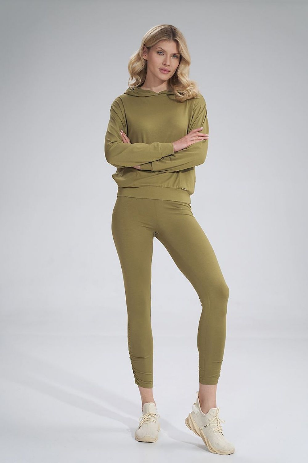 Front view of a stylish model in Figl luxurious long leggings, complementing a trendy hooded sweatshirt in olive hue, ideal for casual elegance.
