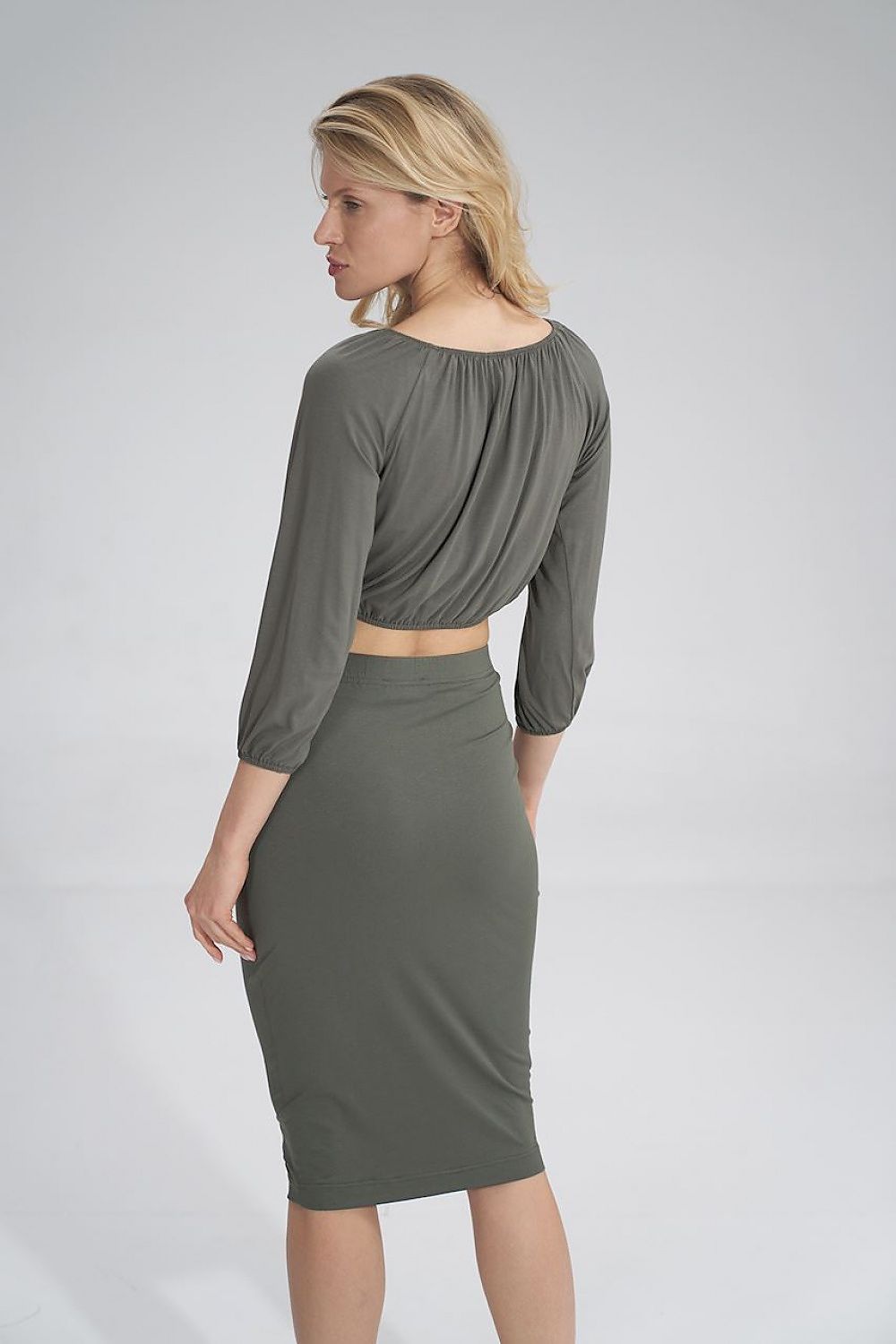 Back view of a stylish model wearing a Figl pleated blouse, revealing a chic olive skirt, perfect for fashionable outings.