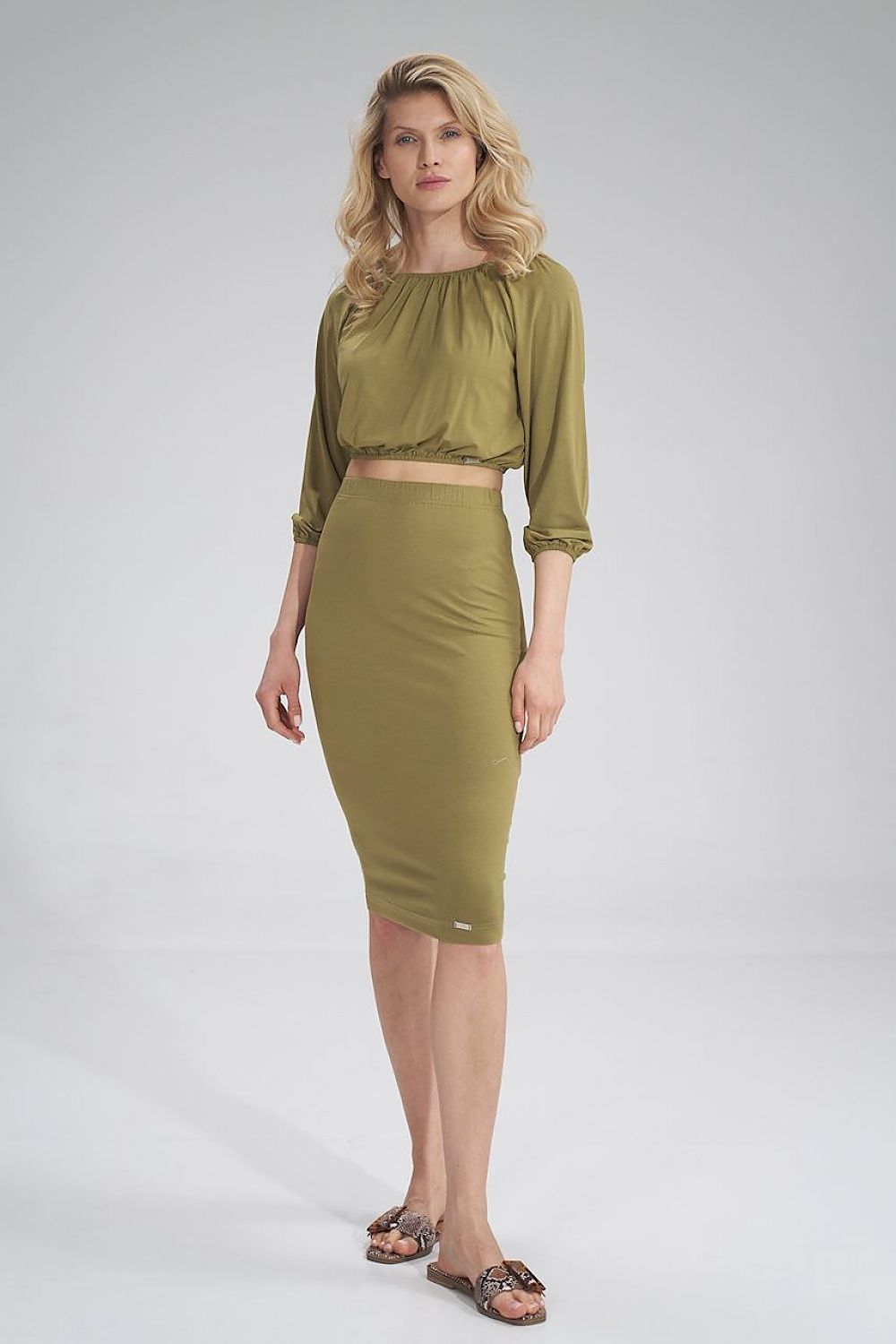 Graceful pose of a model wearing an olive green blouse and pencil skirt, embodying sophisticated fashion by Figl.