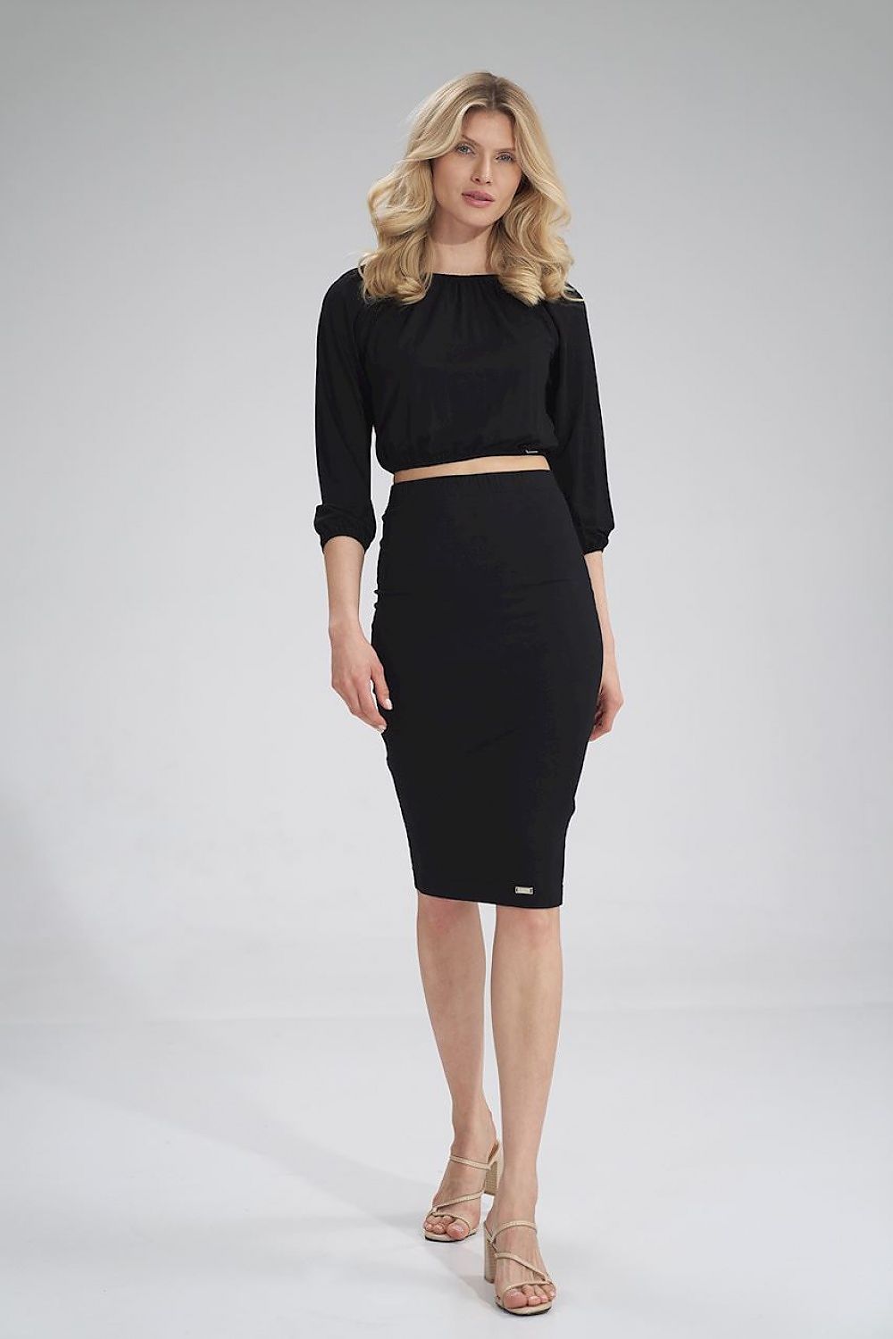 Confident stance of a woman in a stylish black Figl 3/4 sleeve pleated blouse and skirt, perfect for luxury attire.