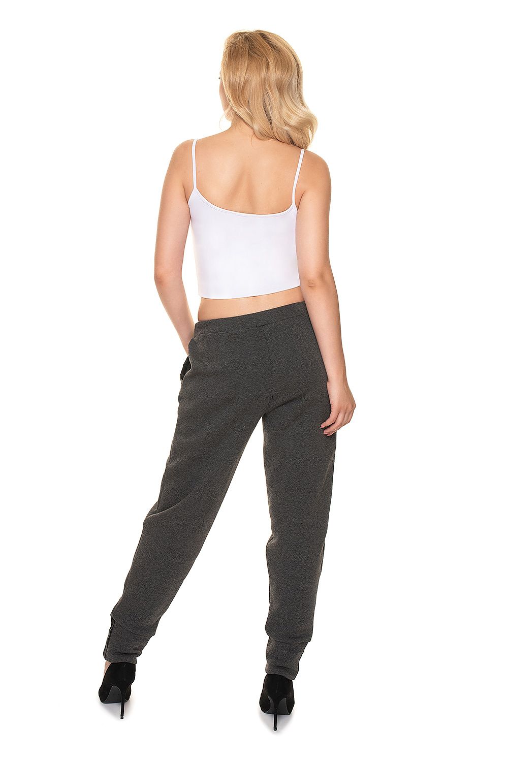 Back view of a woman wearing PeeKaBoo Luxe Loose-Fit Tracksuit Trousers with Eco-Leather Inserts, featuring a luxurious loose-fit design, styled with a white crop top.