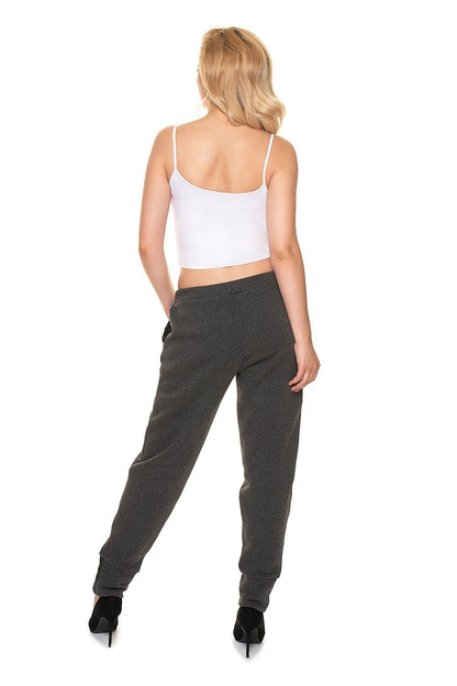 Back view of a woman wearing PeeKaBoo Luxe Loose-Fit Tracksuit Trousers with Eco-Leather Inserts, featuring a luxurious loose-fit design, styled with a white crop top.