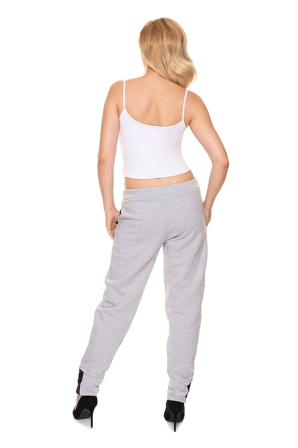 Back view of a woman wearing PeeKaBoo Luxe Loose-Fit Tracksuit Trousers with Eco-Leather Inserts, styled in grey, paired with stiletto heels for an elegant touch.