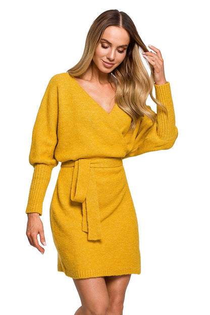 A stunning model presents the Elegant Moe Sweater Dress with Side Ties, Wide Sleeves, and Deep Overlap Neckline in a vibrant mustard colour, accentuating style with a modern twist.