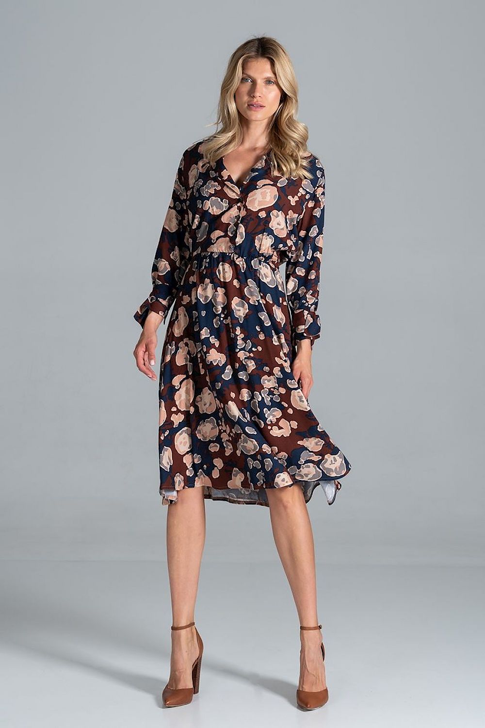 A model wearing the Elegant Midi Dress by Figl in a floral print with a jacket-style v-neck and flared hem, complemented with stylish high heels.