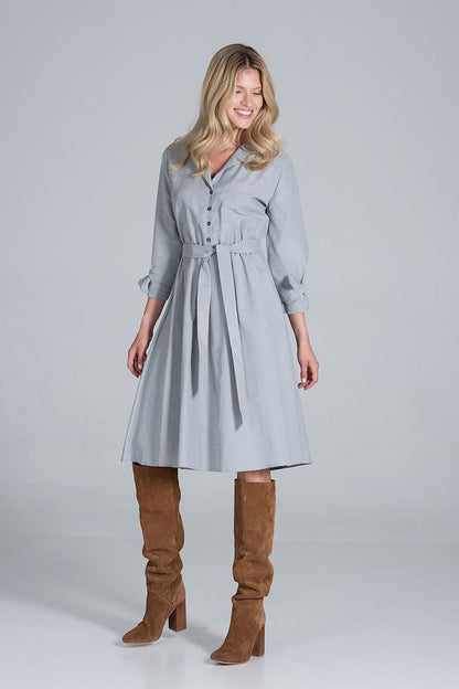Elegant Midi Dress by Figl with Jacket-Style V-Neck, Flared Hem & Tie Belt, styled in a light grey fabric, displayed with a cheerful smile and knee-high brown boots, embodying sophistication and elegance.