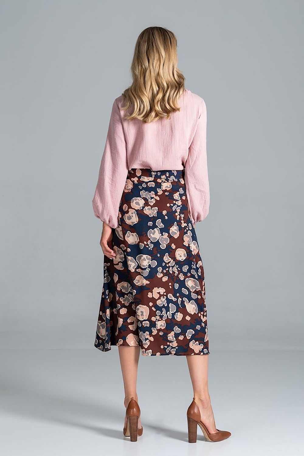 Back view of the Luxury Figl Blouse with half-round neckline and long sleeves, elegantly styled with a floral skirt.