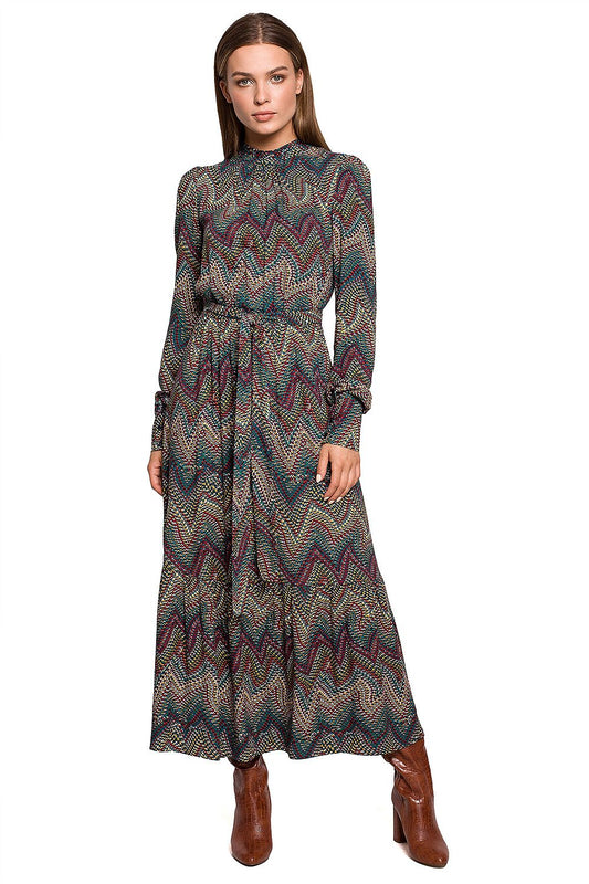 Stylove Aztec Pattern Daydress featuring a ruffle hem and stand-up collar, elegantly styled for autumn. Model showcases the dress with a chic ankle boot ensemble.