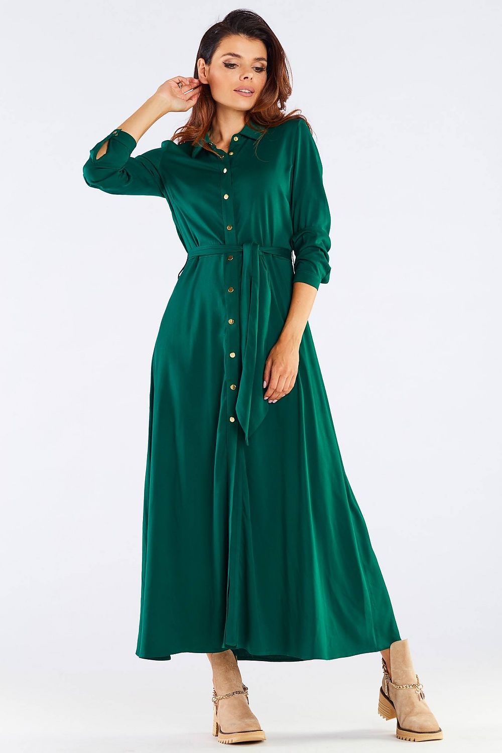 Chic view of the maxi dress with buttoned trapeze bottom and collared belt, model posing gracefully while adjusting her hair, highlighting the dress's luxurious design.