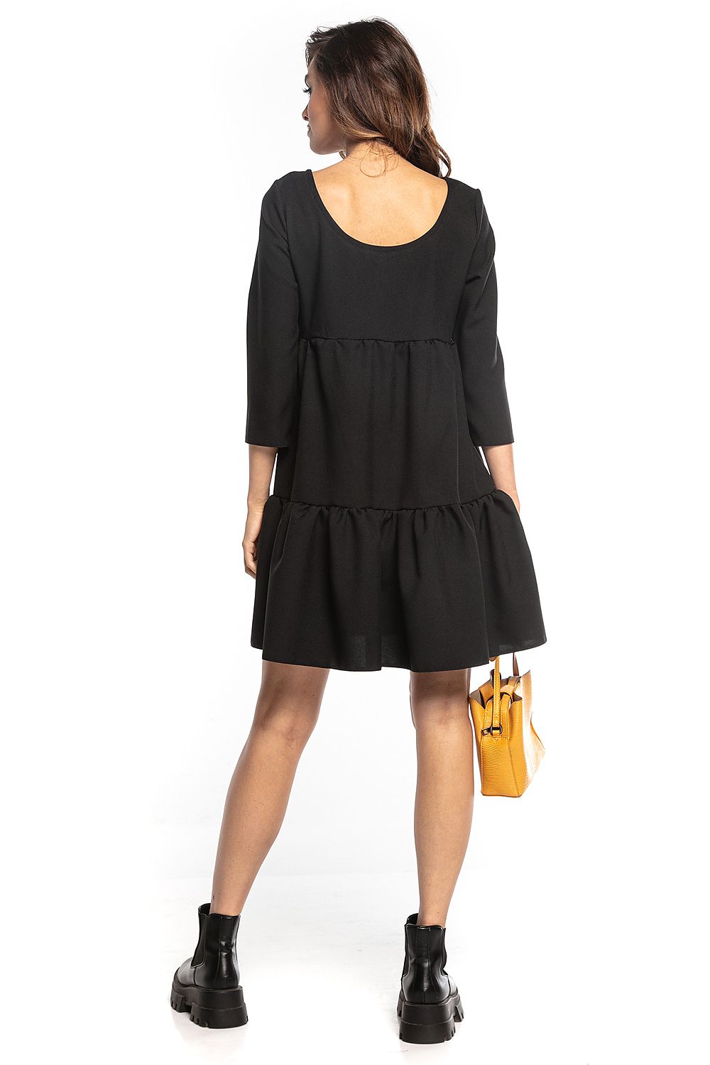Back view of a model in a sophisticated black mini dress featuring ruffled flared design, 3/4 sleeves, and a deep neckline, presented by Tessita.
