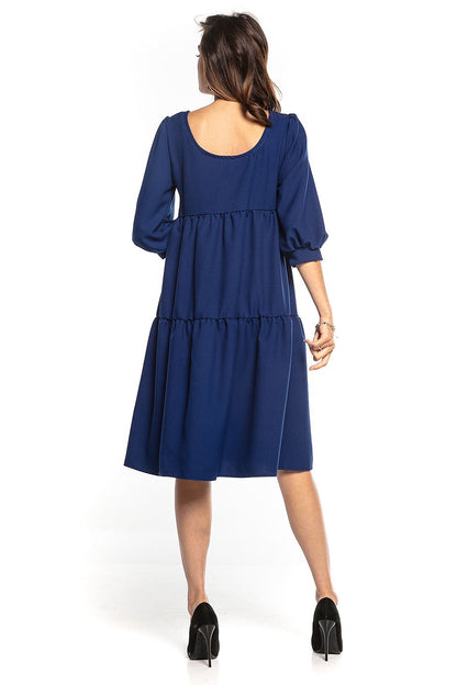 Back view of a luxury navy blue bouffant sleeve day dress with ruffles and flared design, tailored by Tessita.