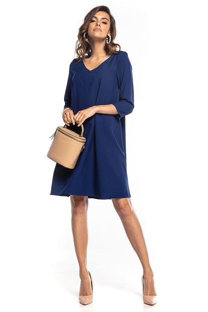 Sophisticated Tessita women's trapeze dress showcasing a minimalist design with 3/4 sleeves and a tasteful pointed neckline, elegantly paired with a stylish bag.