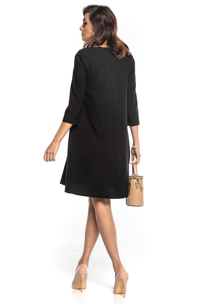 Elegant trapeze dress in black by Tessita, featuring 3/4 sleeves and a flattering pointed neckline. Styled with a chic decorative belt, perfect for sophisticated occasions.