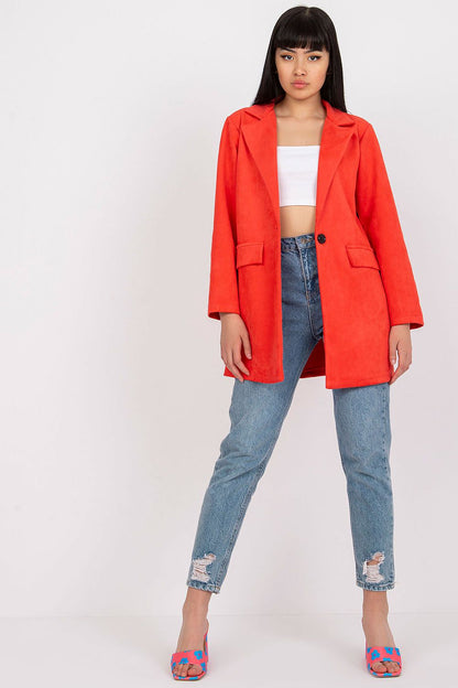 Chic model in a striking red imitation suede jacket and cropped top, standing confidently in distressed jeans and colourful heels, embodying modern elegance for a fashionable outfit.
