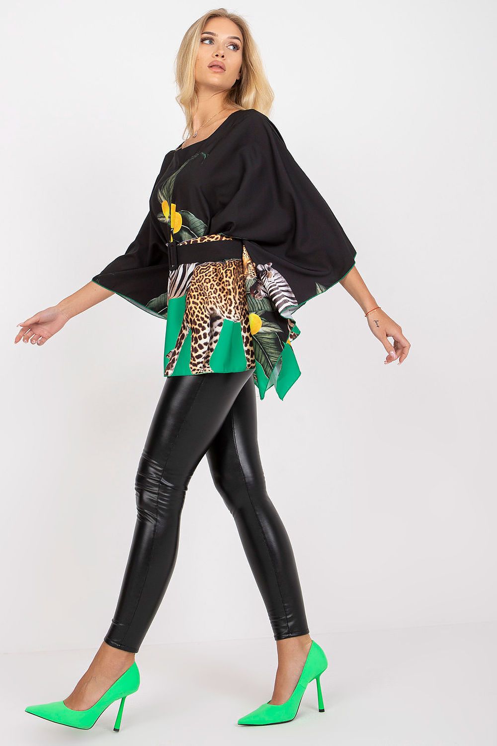 Elegant side view of Italy Moda loose cut blouse showcasing unique patterns, complemented by black leggings and striking green heels, ideal for both casual and formal occasions.
