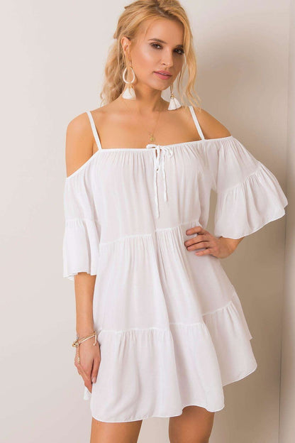 Elegant white summer dress featuring an asymmetrical cut, frills, and 3/4 sleeves, styled with a charming tied neckline; perfect for warm-weather occasions.