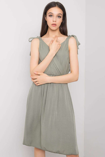 Elegant ochre sleeveless viscose daydress featuring an envelope neckline and delicate tie straps, perfect for summer outings. Styled for sophistication in a soft green hue.