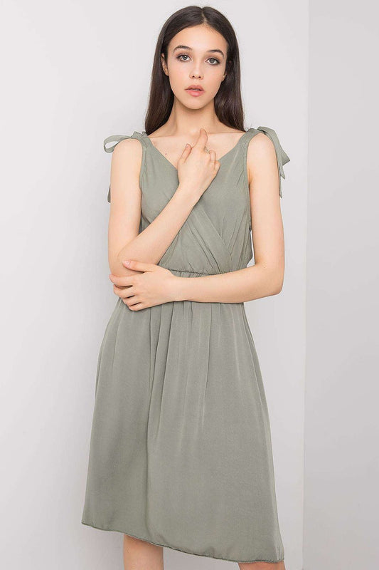 Elegant ochre sleeveless viscose daydress featuring an envelope neckline and delicate tie straps, perfect for summer outings. Styled for sophistication in a soft green hue.