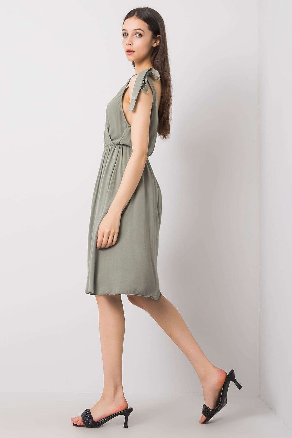 Side view of an exquisite Och Bella sleeveless daydress in soft green, showcasing a flowing silhouette and stylish tie straps for a sophisticated summer look.
