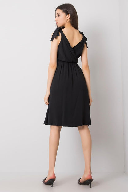 Back view of a sophisticated black sleeveless daydress by Och Bella, featuring delicate tie straps and a cinched waist, embodying luxurious summer style.