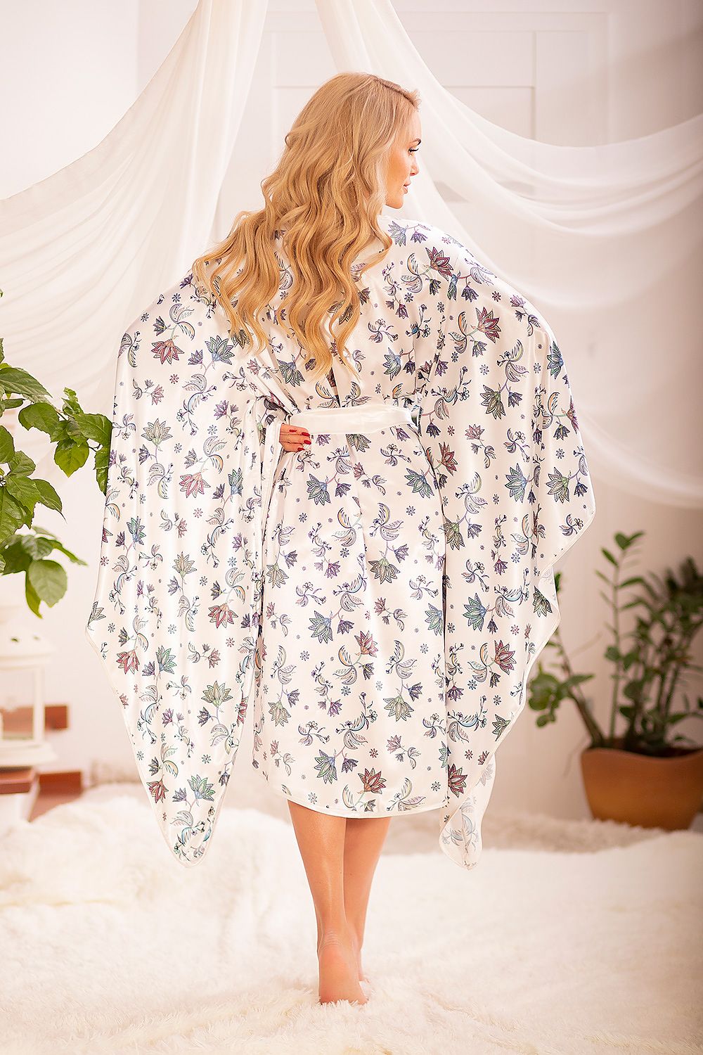 Back view of a model in a Kalimo satin chemise bathrobe with wide sleeves and floral patterns, highlighting the robe's luxurious design and perfect fit for elegant loungewear.