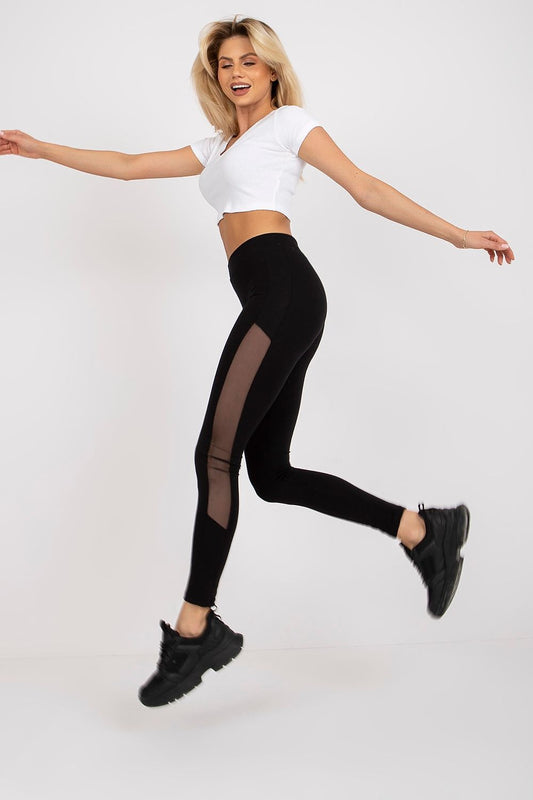 Elegant model in motion wearing luxury black leggings with mesh inserts, complemented by a trendy cropped white top. Perfect for a sophisticated yet sporty look.