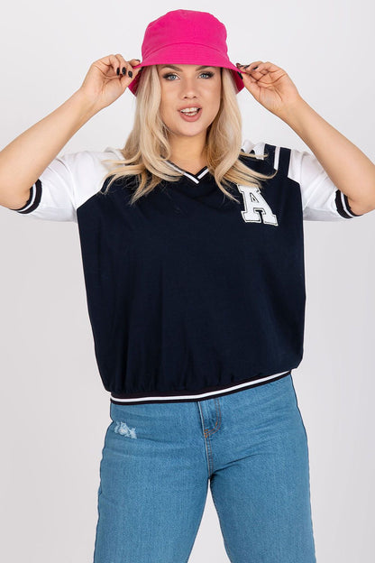 Fashionable model in a navy oversized blouse with contrasting white sleeves and an embroidered 'A', paired with a pink bucket hat for a vibrant touch.