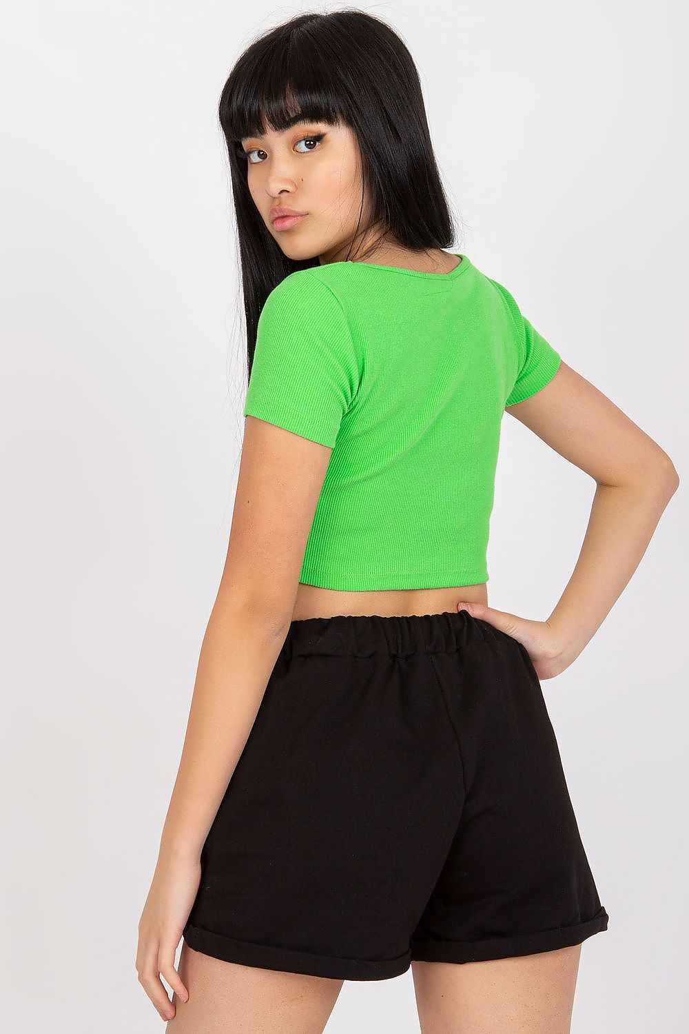 Stylish woman in luxury cotton sweatshorts posing confidently, showcasing the black fabric and comfortable fit against a minimalist backdrop.