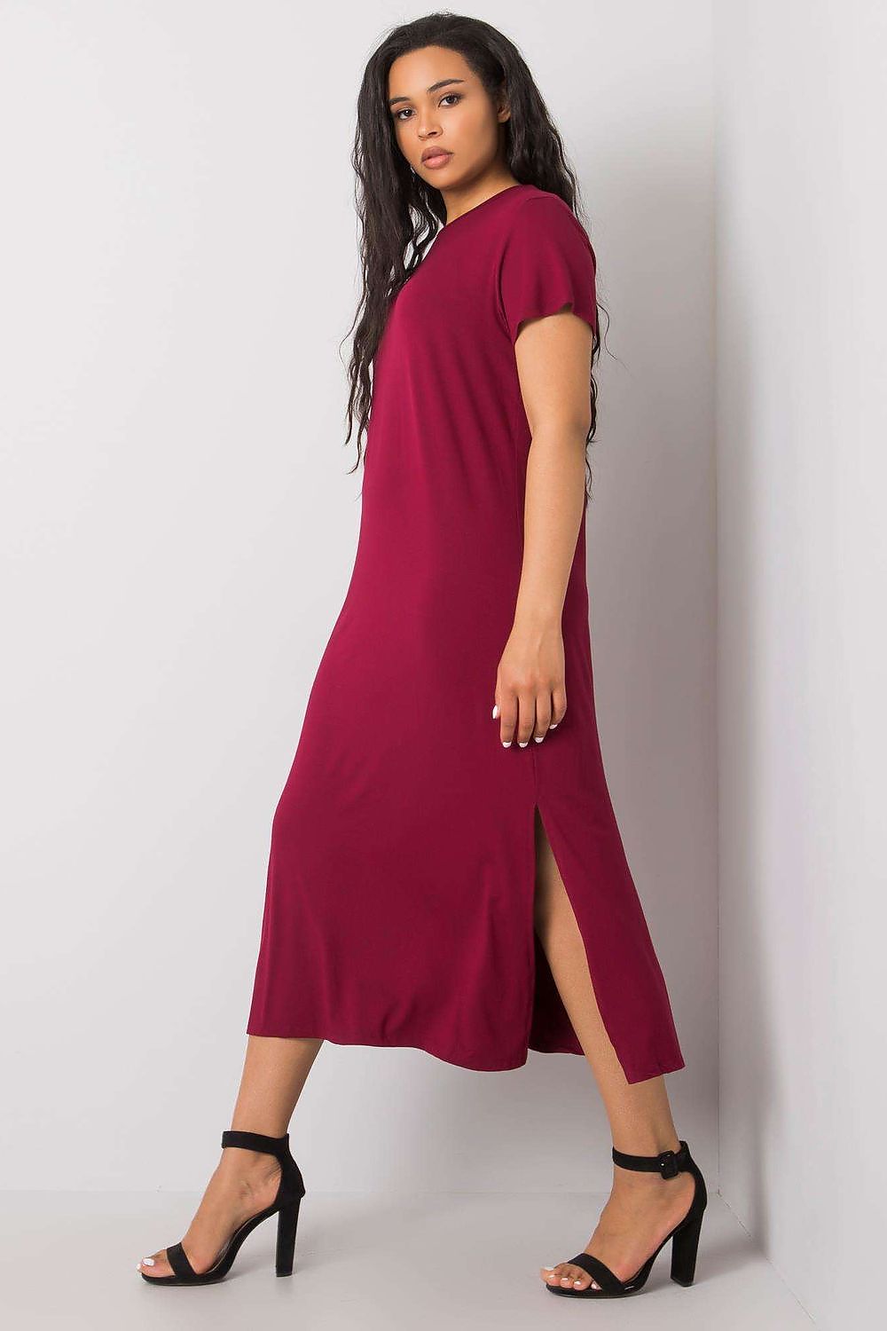 Fashionable plus size summer dress in burgundy by BFG, with a luxurious fit and slit design, displayed by model in elegant heels, perfect for upscale summer occasions.