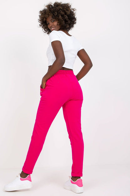 Stunning rear view of a woman in luxe pink BFG tracksuit trousers, highlighting the flattering high-waist design, styled with a fitted cropped top and white sneakers, capturing modern elegance.
