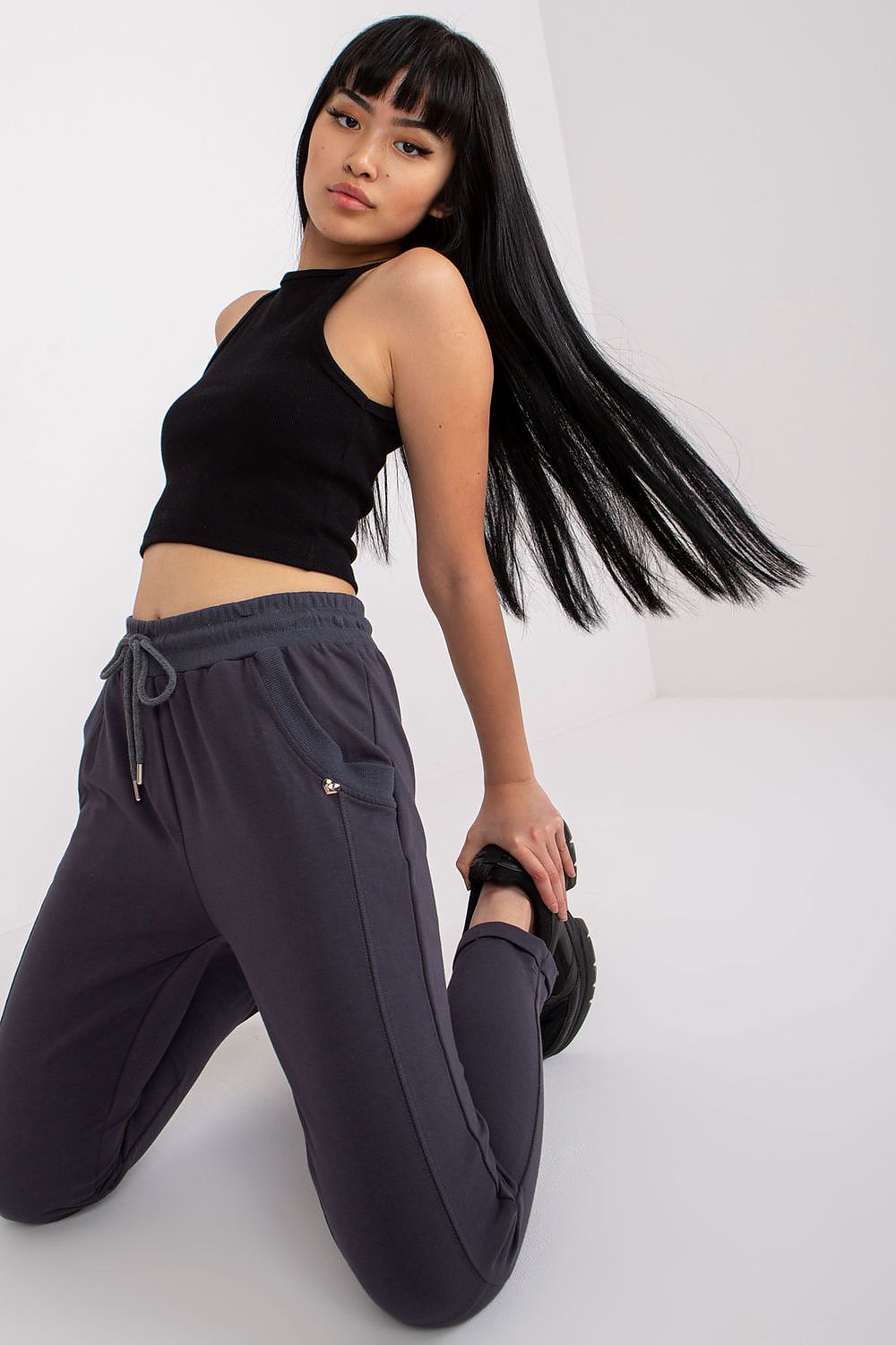 Sleek model posing in high-waist grey tracksuit trousers with a stylish black crop top, exuding an air of contemporary luxury and comfort.