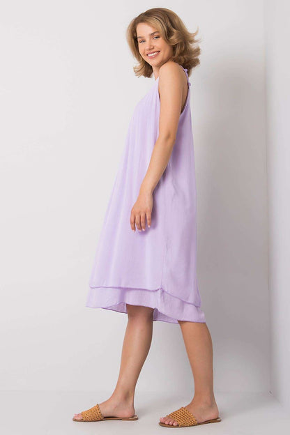 Elegantly Designed Summer Dress With Decorative Straps By Och Bella - Side view of a model wearing a lavender summer dress, highlighting its flowing silhouette and versatile design.